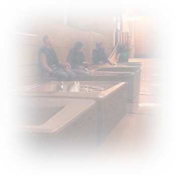 Three figures seated in metal trough-like compartments